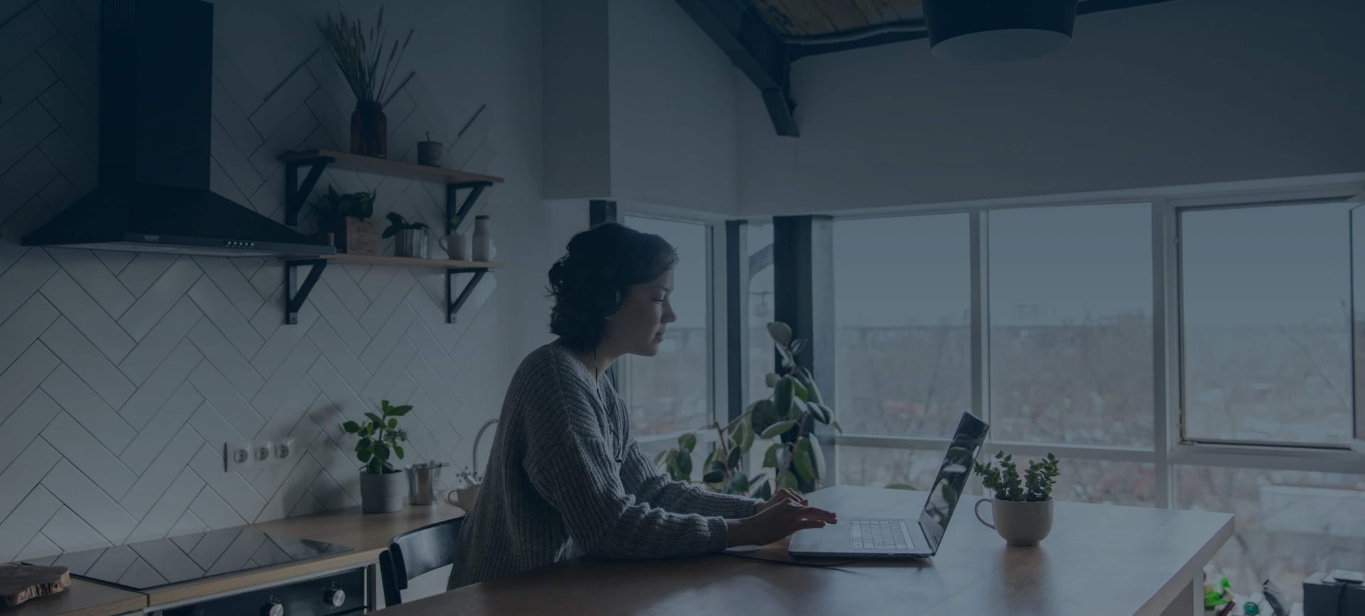 Woman working from home at kitchen bench on laptop.