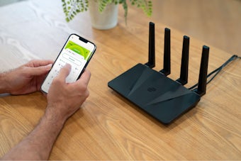 Lifestyle image of ExpressVPN Aircove with a smartphone.