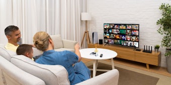 Imagem do estilo de vida do ExpressVPN Aircove ao lado de uma TV com uma família assistindo.
