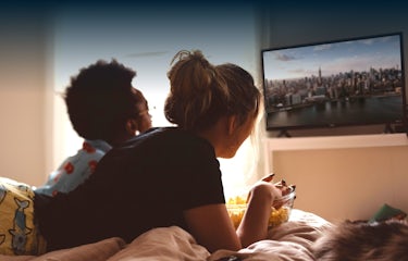 Couple watching TV and eating popcorn.