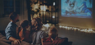 En familie ser tv på en projektor.